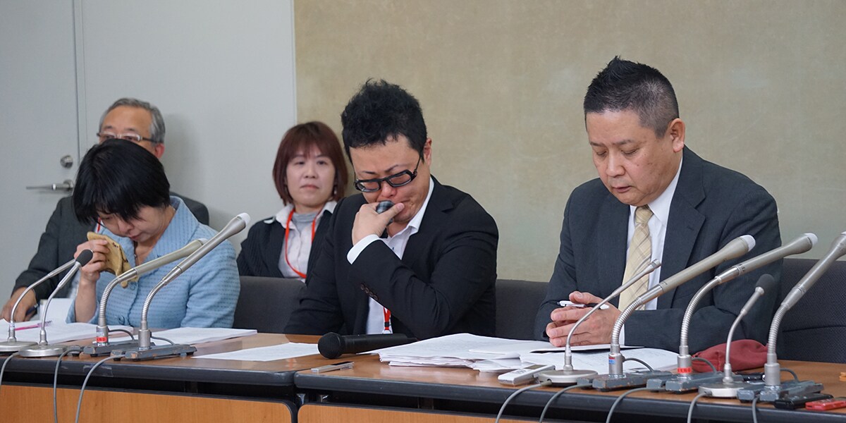 中労委命令後の会見で涙をぬぐう高橋さん（中央）