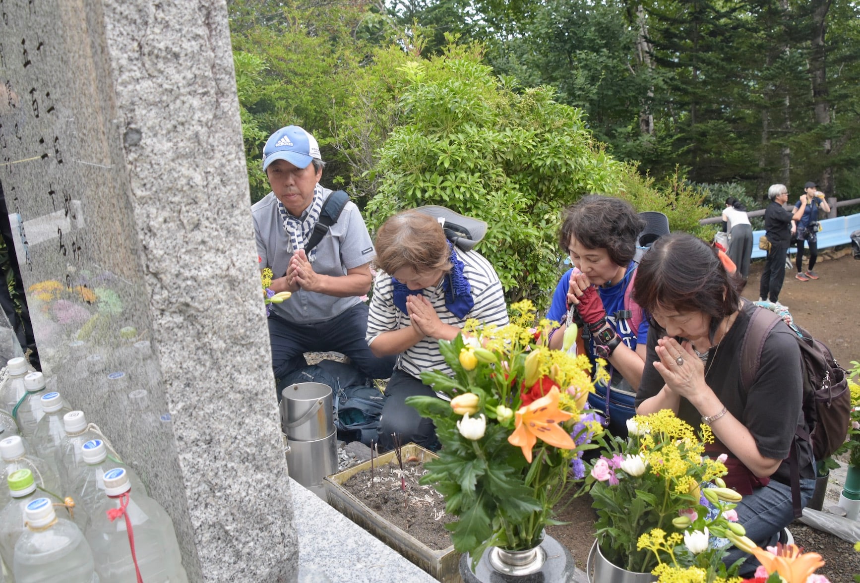 「昇魂之碑」の前で手を合わせる（左から）田村孝行さん、妻の弘美さん、高橋幸美さん、安部宏美さん（弁護士ドットコムニュース撮影）